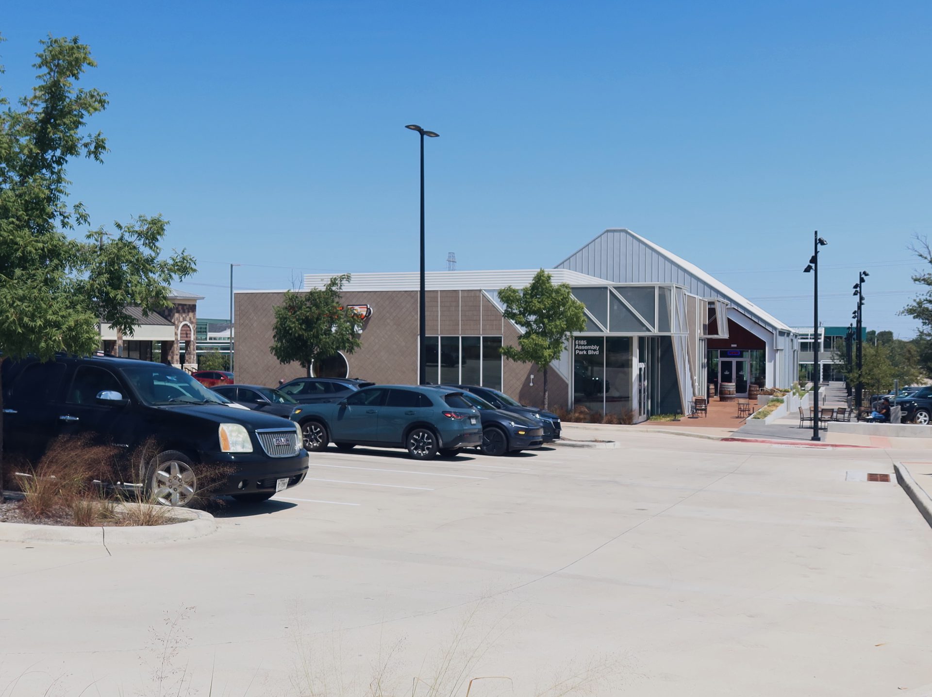 The view from the Assembly Park parking lot toward Cliff Coffee, showing the glass gable with the 6185 Assembly Park Blvd address panel