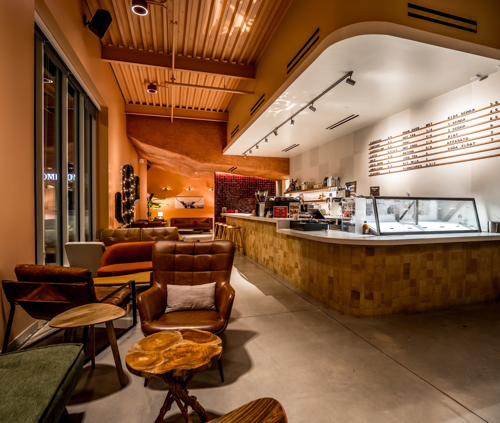 Inside Cliff Coffee: leather lounge chairs in front of the counter, with the menu board and the scoop case behind